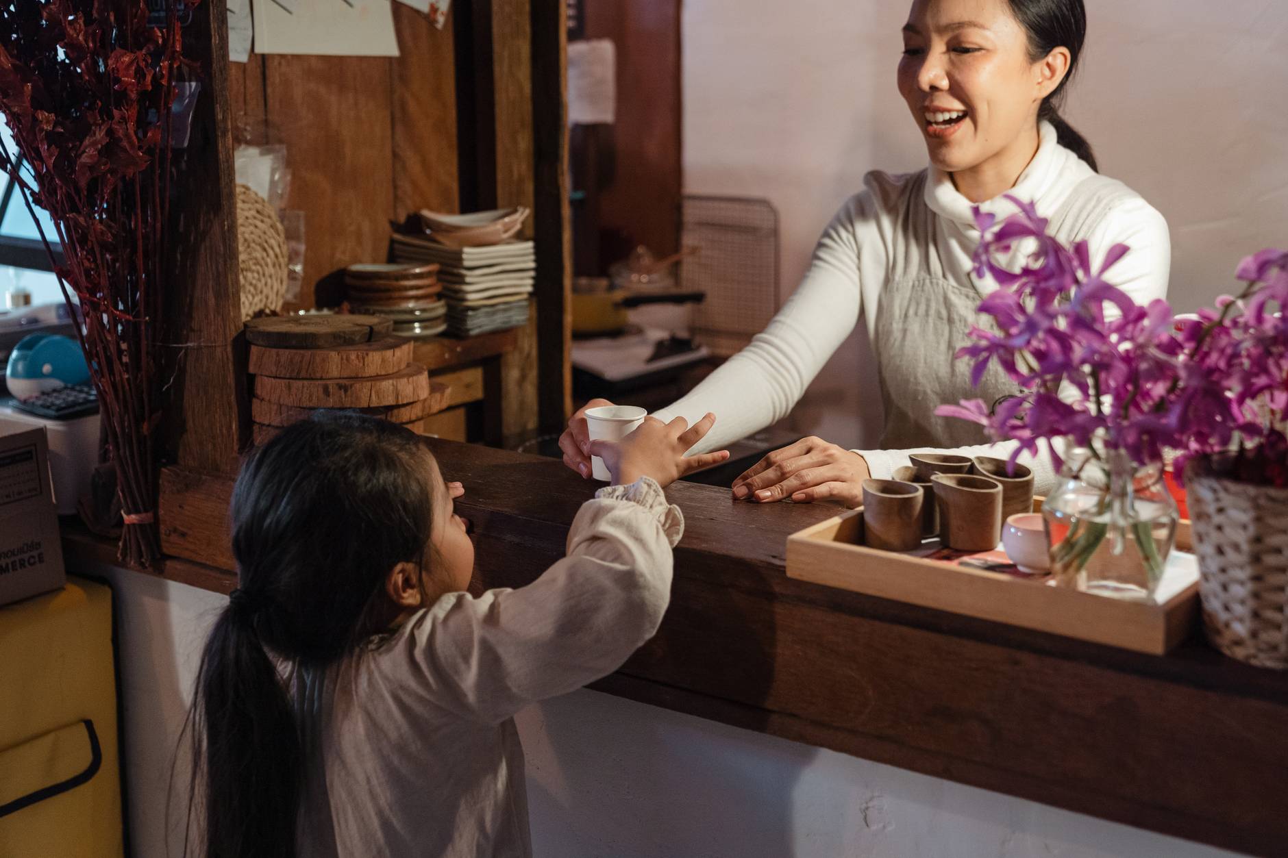crop ethnic mother serving little girl glass of refreshing drink