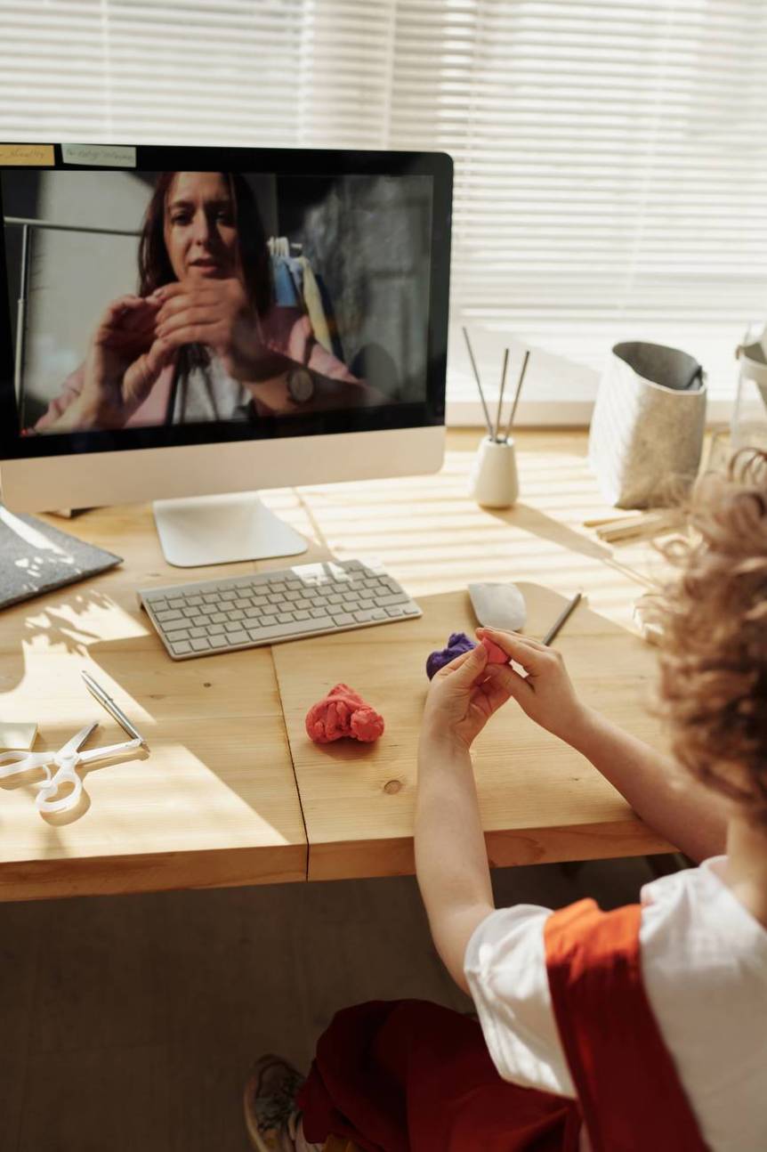 photo of kid playing with kinetic sand while watching through imac
